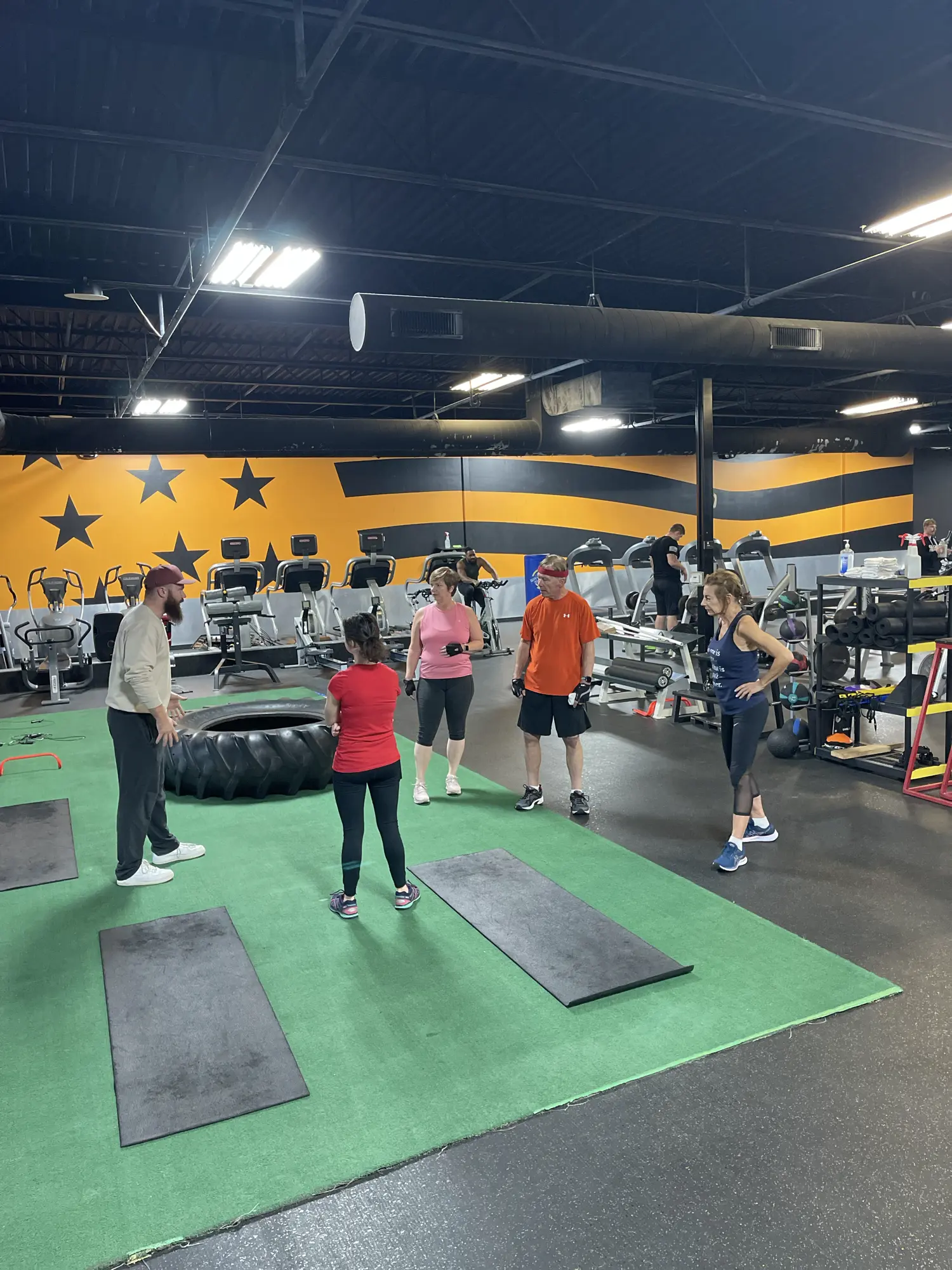 Local fitness trainer working in a semi-private setting with students to improve their strength